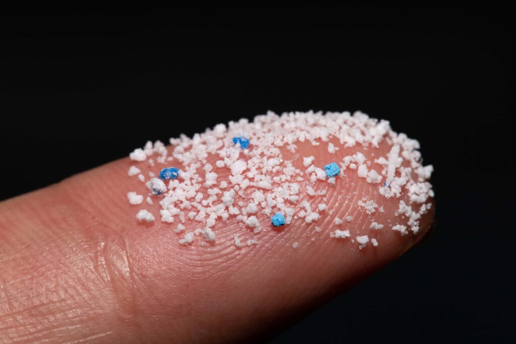 Close-up image of microplastics adhered to a finger, highlighting the tiny plastic particles present in the environment